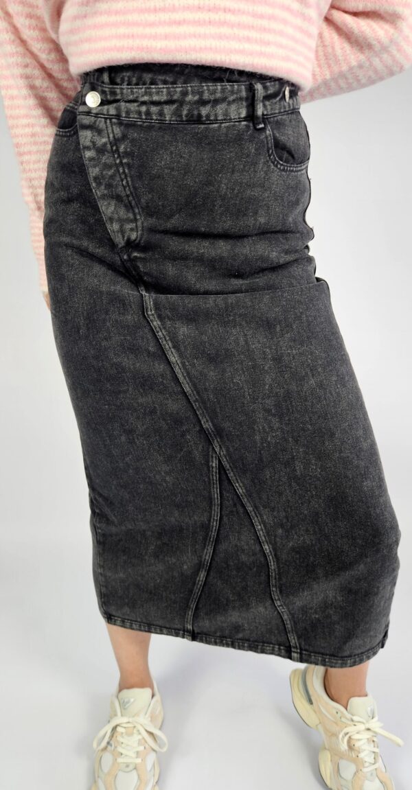 Modna spódnica jeansowa o klasycznym kroju, wyróżniająca się oryginalnym zapięciem z przodu i stylowym rozporkiem, który dodaje swobody ruchów. Wykonana z trwałego denimu, doskonale sprawdzi się w casualowych stylizacjach przez cały rok.