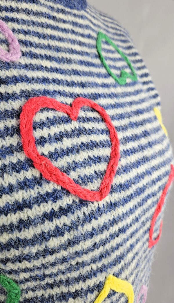 Sweter heart Uroczy, miękki sweter w kolorze niebieskim, ozdobiony wzorem w serca. Wykonany z przyjemnej dzianiny z dodatkiem wełny, która zapewnia ciepło i komfort noszenia. Idealny na chłodne, codzienne stylizacje z nutą romantyzmu.