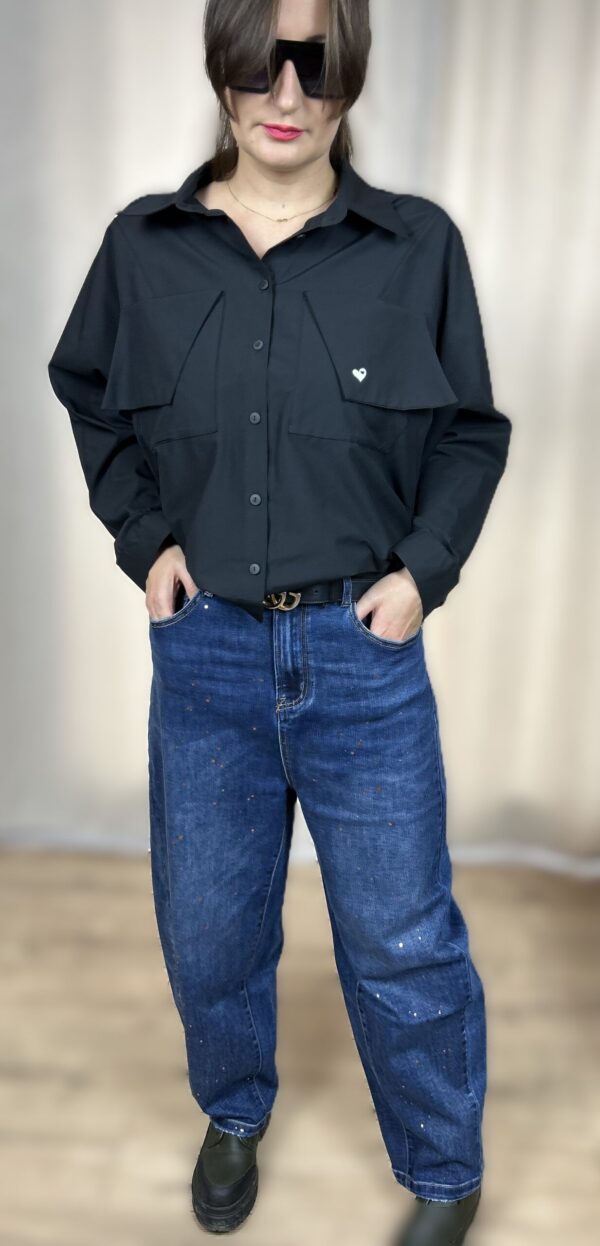 Stylowa, krótka koszula zapinana na guziki, z długim rękawem zakończonym mankietem. Na piersi dwie kieszenie z klapami, z których jedna ozdobiona jest subtelnym, wyszywanym serduszkiem. Idealna do nowoczesnych, codziennych i lekko romantycznych stylizacji.