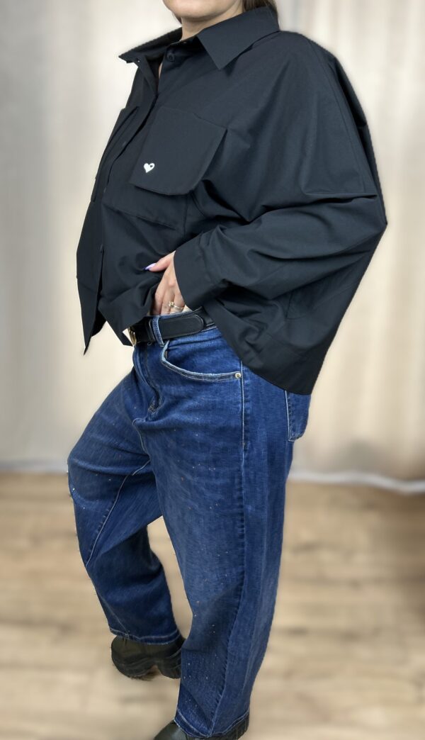 Stylowa, krótka koszula zapinana na guziki, z długim rękawem zakończonym mankietem. Na piersi dwie kieszenie z klapami, z których jedna ozdobiona jest subtelnym, wyszywanym serduszkiem. Idealna do nowoczesnych, codziennych i lekko romantycznych stylizacji.