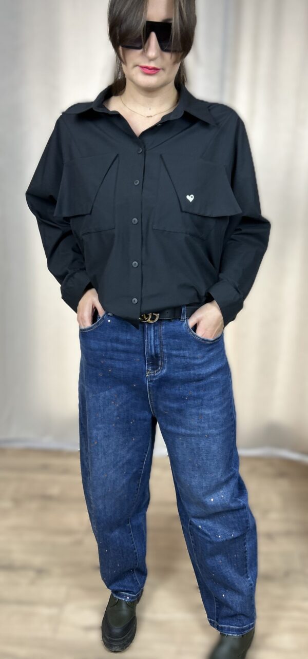 Stylowa, krótka koszula zapinana na guziki, z długim rękawem zakończonym mankietem. Na piersi dwie kieszenie z klapami, z których jedna ozdobiona jest subtelnym, wyszywanym serduszkiem. Idealna do nowoczesnych, codziennych i lekko romantycznych stylizacji.